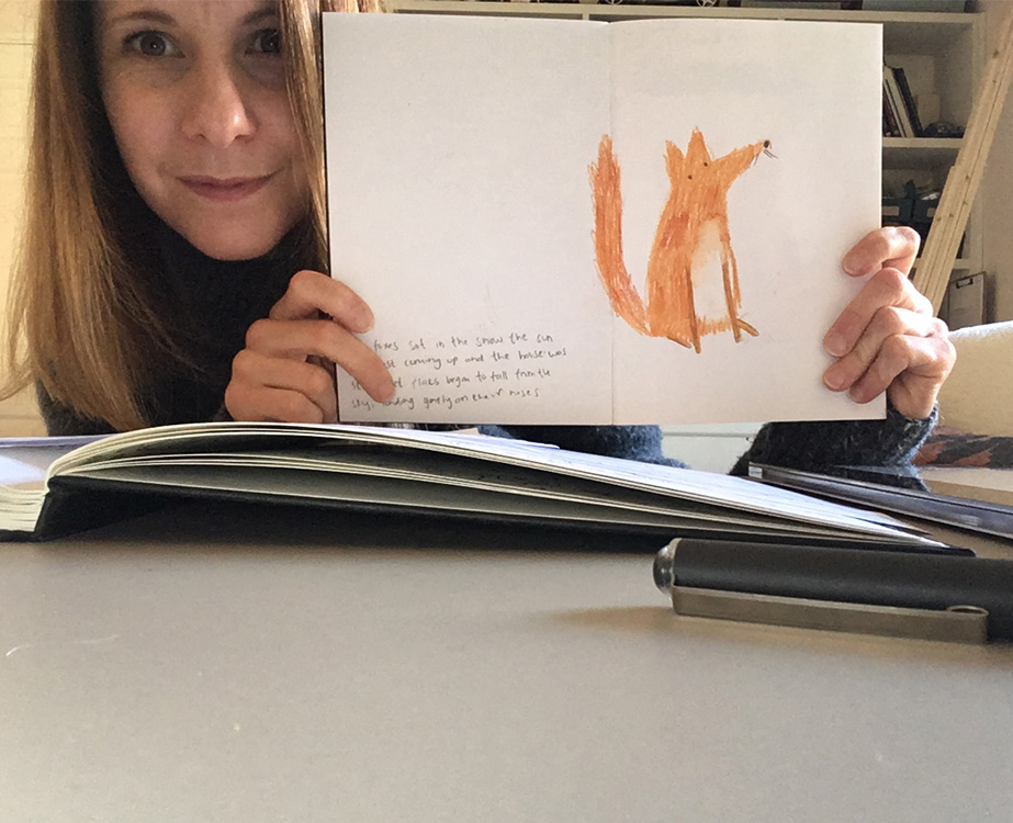 Sarah holding up sketchbook with fox wax crayon drawing