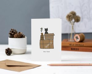 Hand illustrated cat on top of boxes with fragile written on them and new home text greeting card
